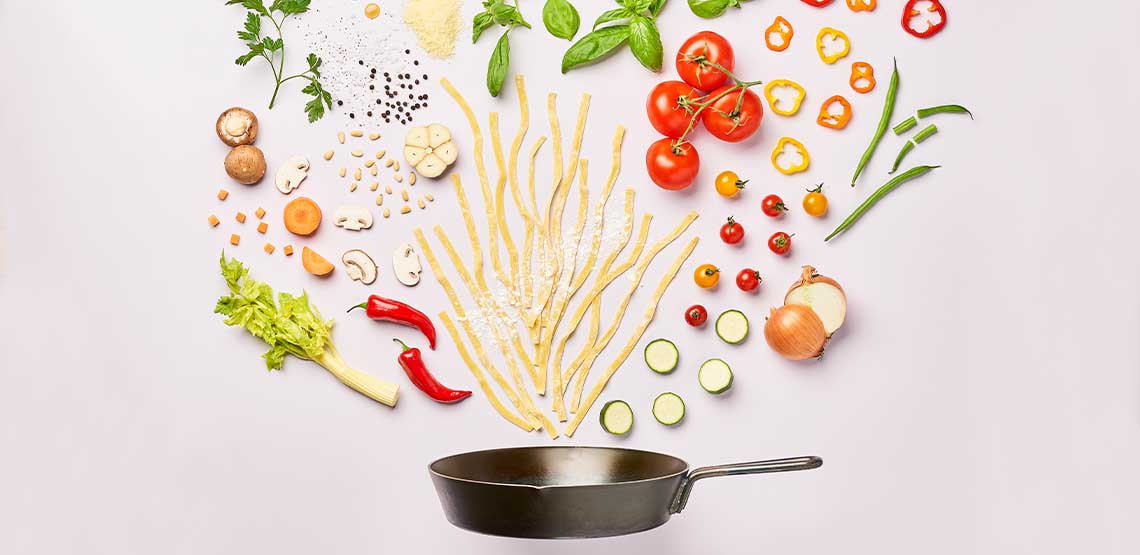 A frying pain with veggies coming out of it.
